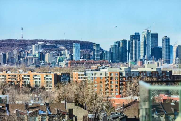Skyline view of Montreal’s downtown towers seen from Côte Saint-Luc, with residential buildings in the foreground and Mount Royal in the background.