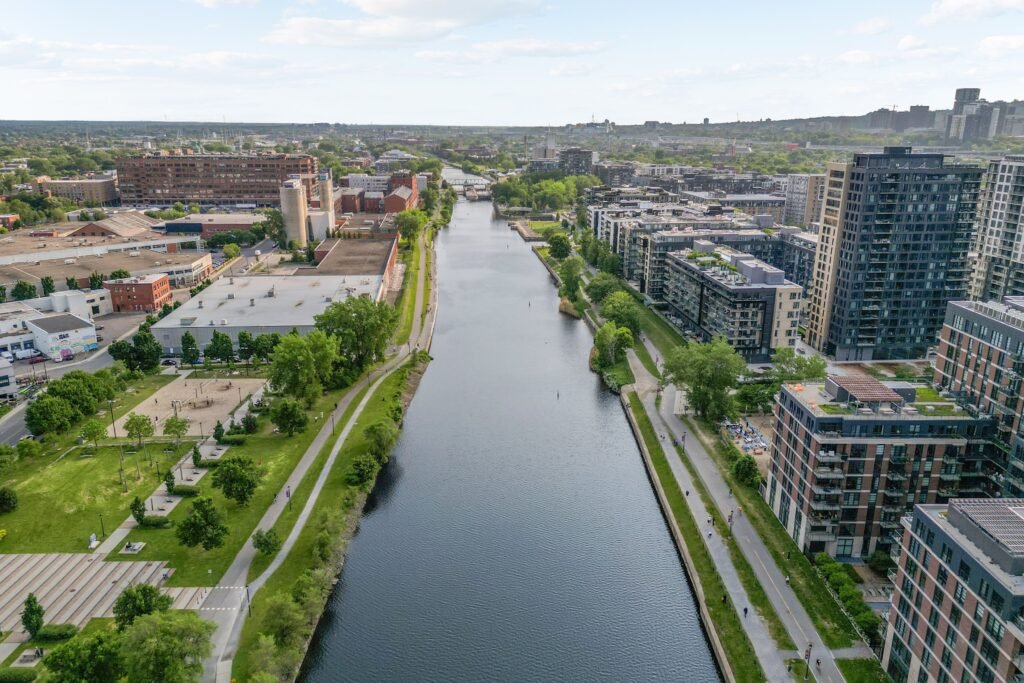 Aerial view of Griffintown, Montreal, showing modern condo buildings, green walkways, and the Lachine Canal.