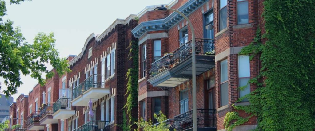 Historic brick apartment buildings in Outremont, Montreal, with wrought-iron balconies and vines growing along the facade.