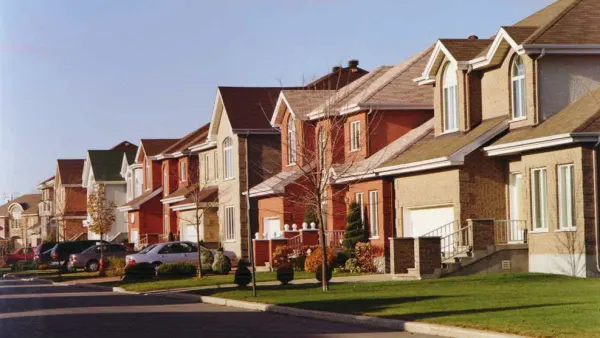 Modern suburban houses in Saint-Laurent, Montreal, with well-kept lawns and cars parked along the street on a sunny day.