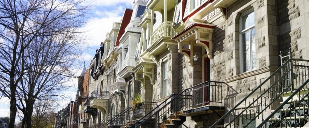 Row of historic stone houses in Westmount, Montreal, featuring ornate balconies and classic architectural details under a bright sky.